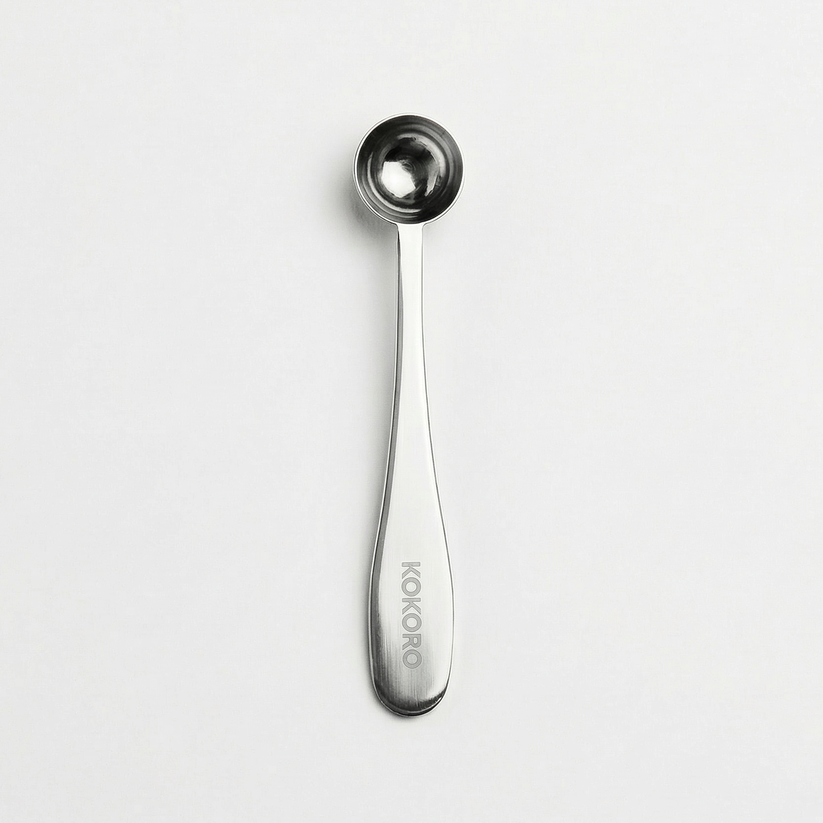 Bamboo matcha scoop (chashaku) used to measure matcha powder, photographed on a light grey background.