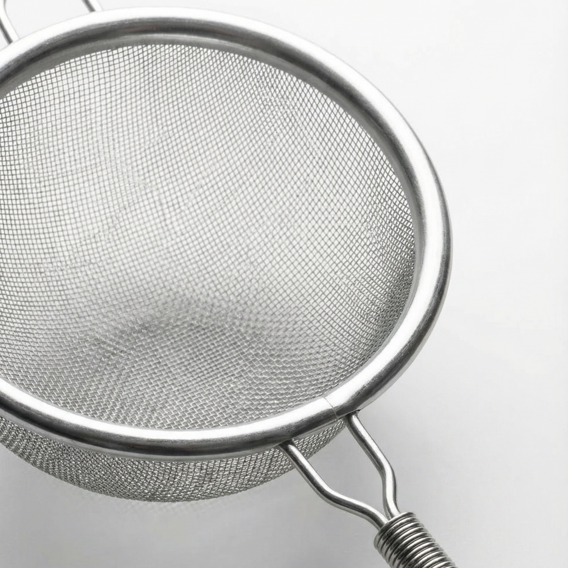 Stainless steel matcha sifter with fine mesh, photographed from above on a light grey background.